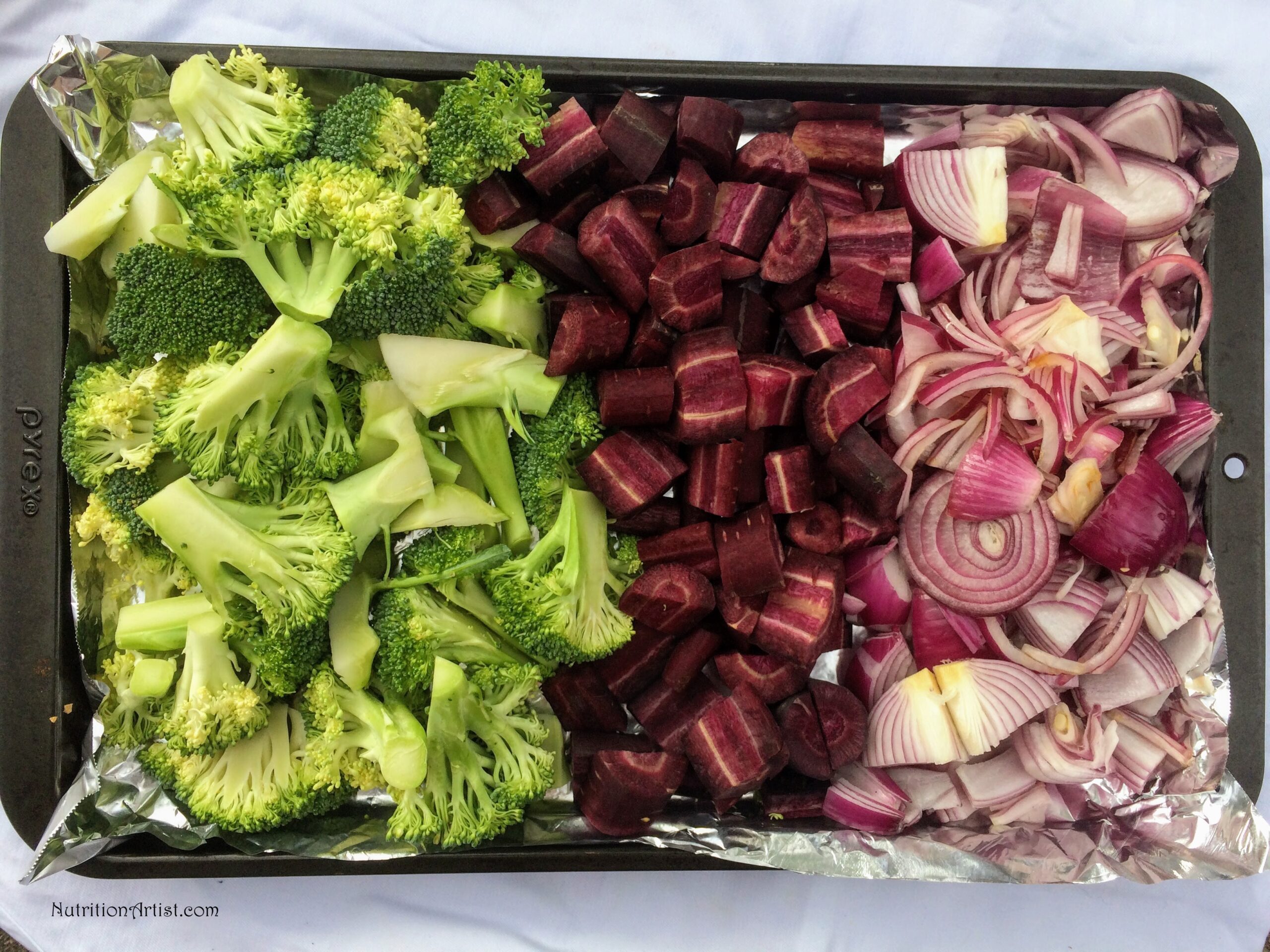 Arranged green, blue and purple vegetables in the order of rainbow colors on a baking sheet.