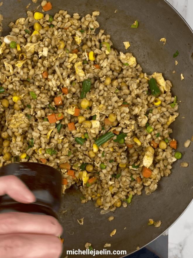 Fresh ground pepper being added to barley fried rice recipe