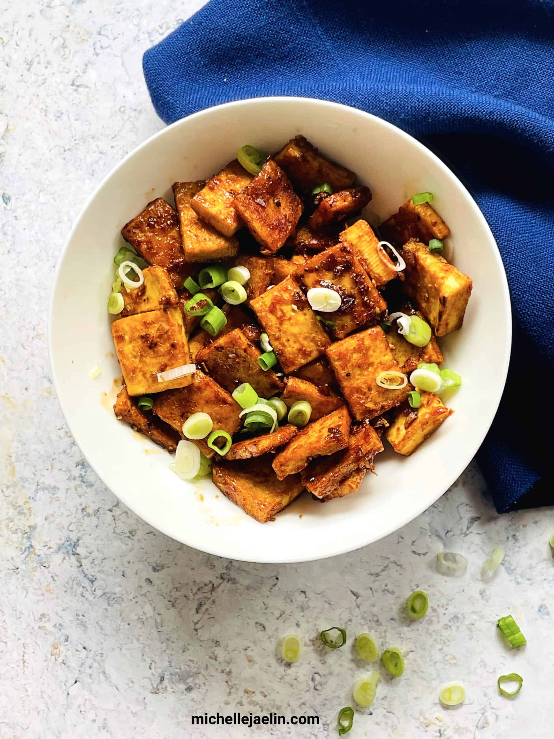 soy garlic tofu in a bowl topped with green onions