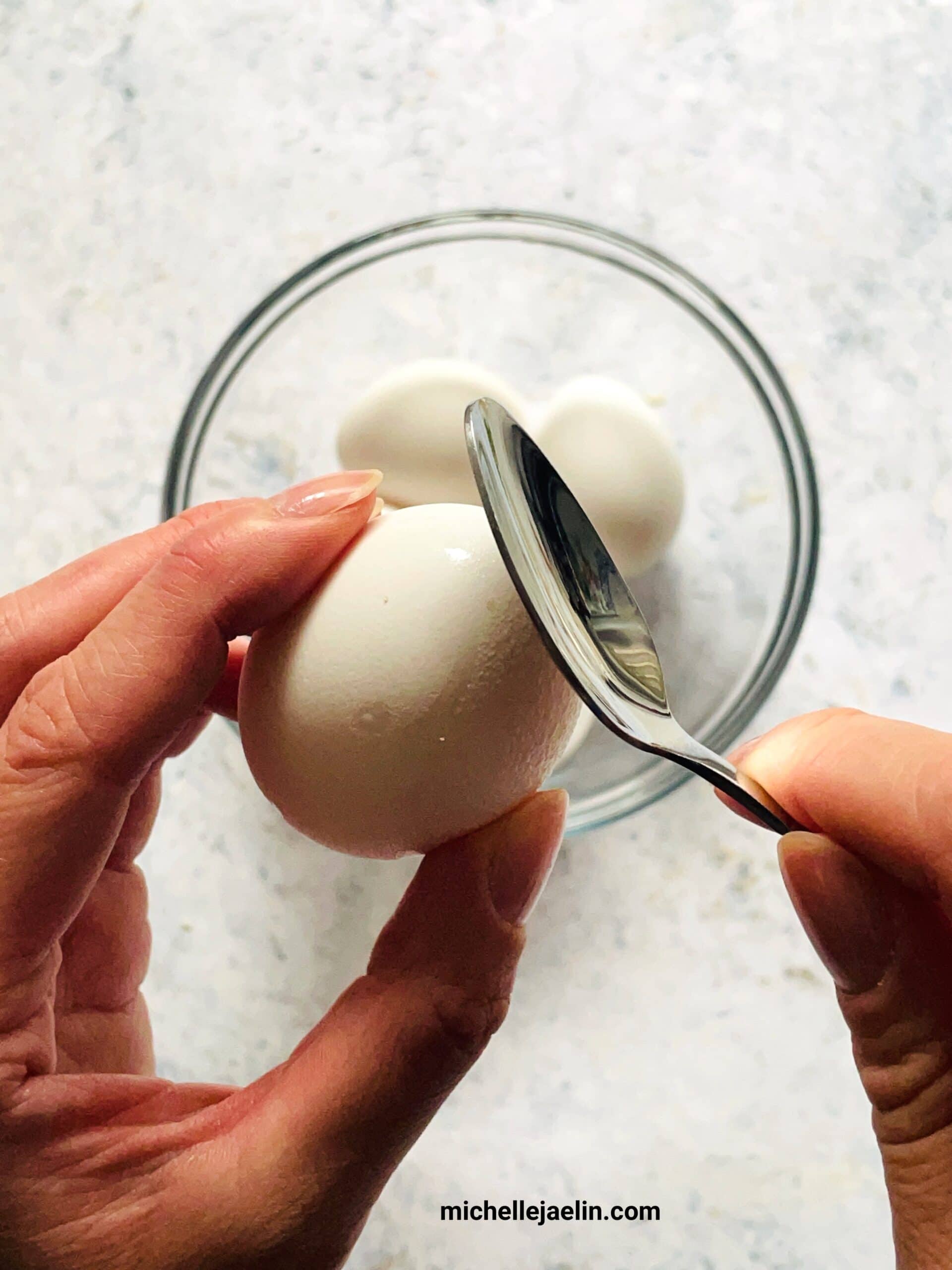 spoon tapping the top of the raw egg shell
