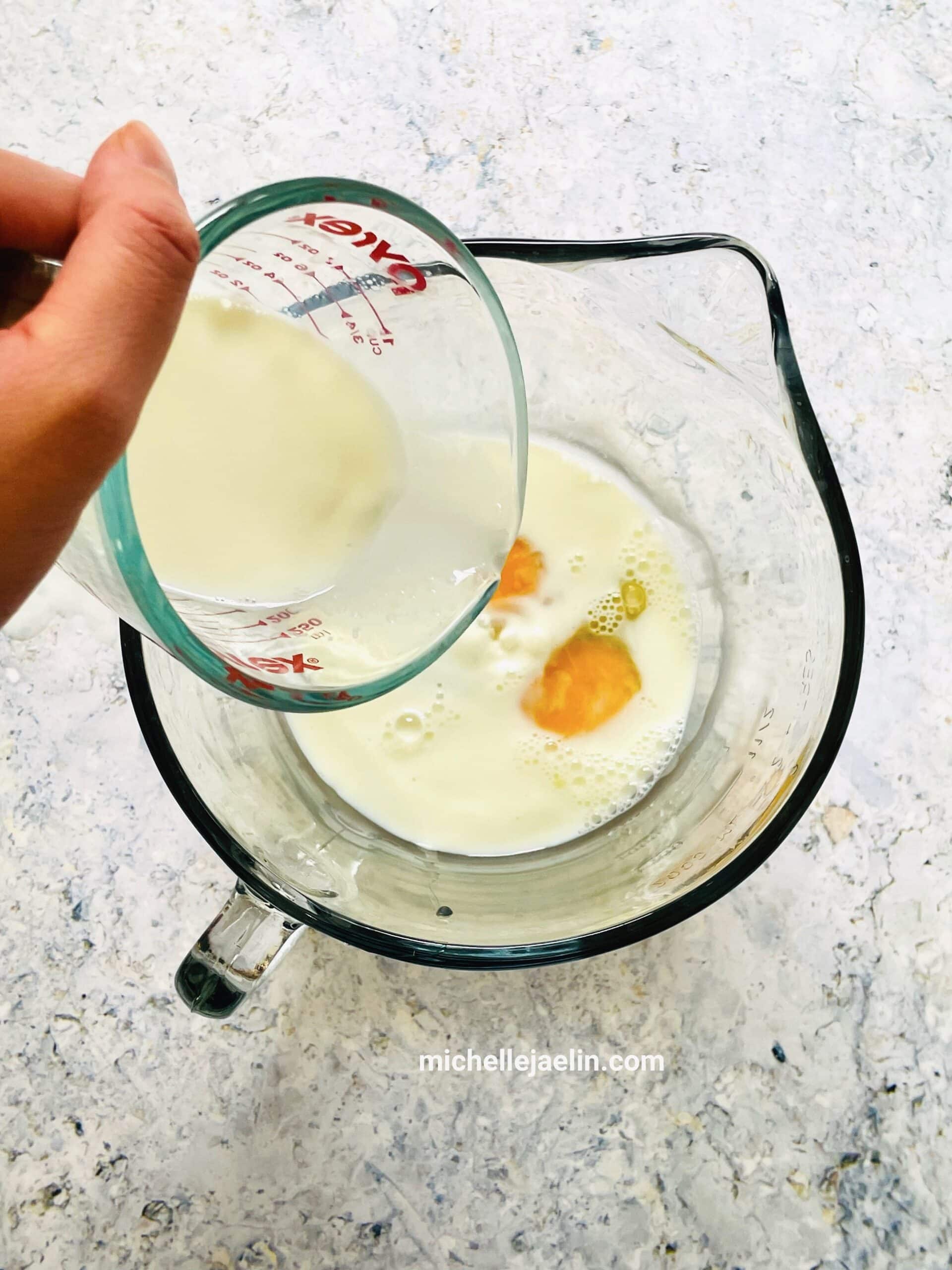 Milk being added to eggs in large bowl