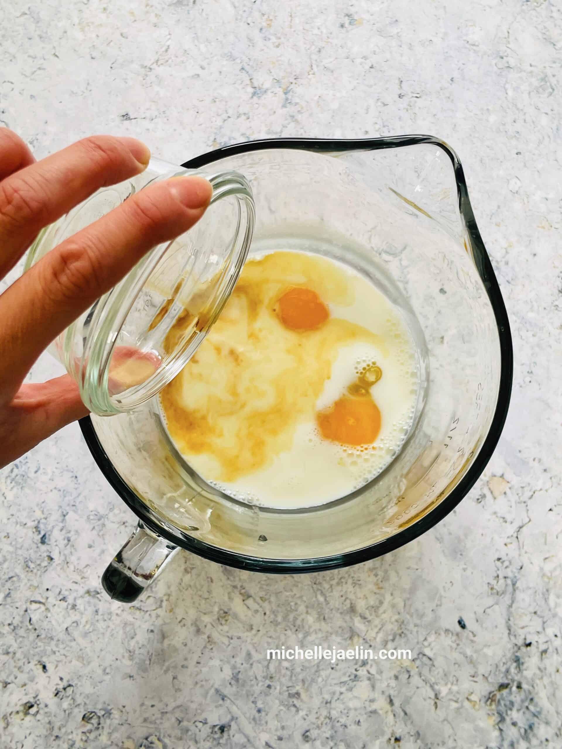 Vanilla extract being added to sugar, milk and eggs