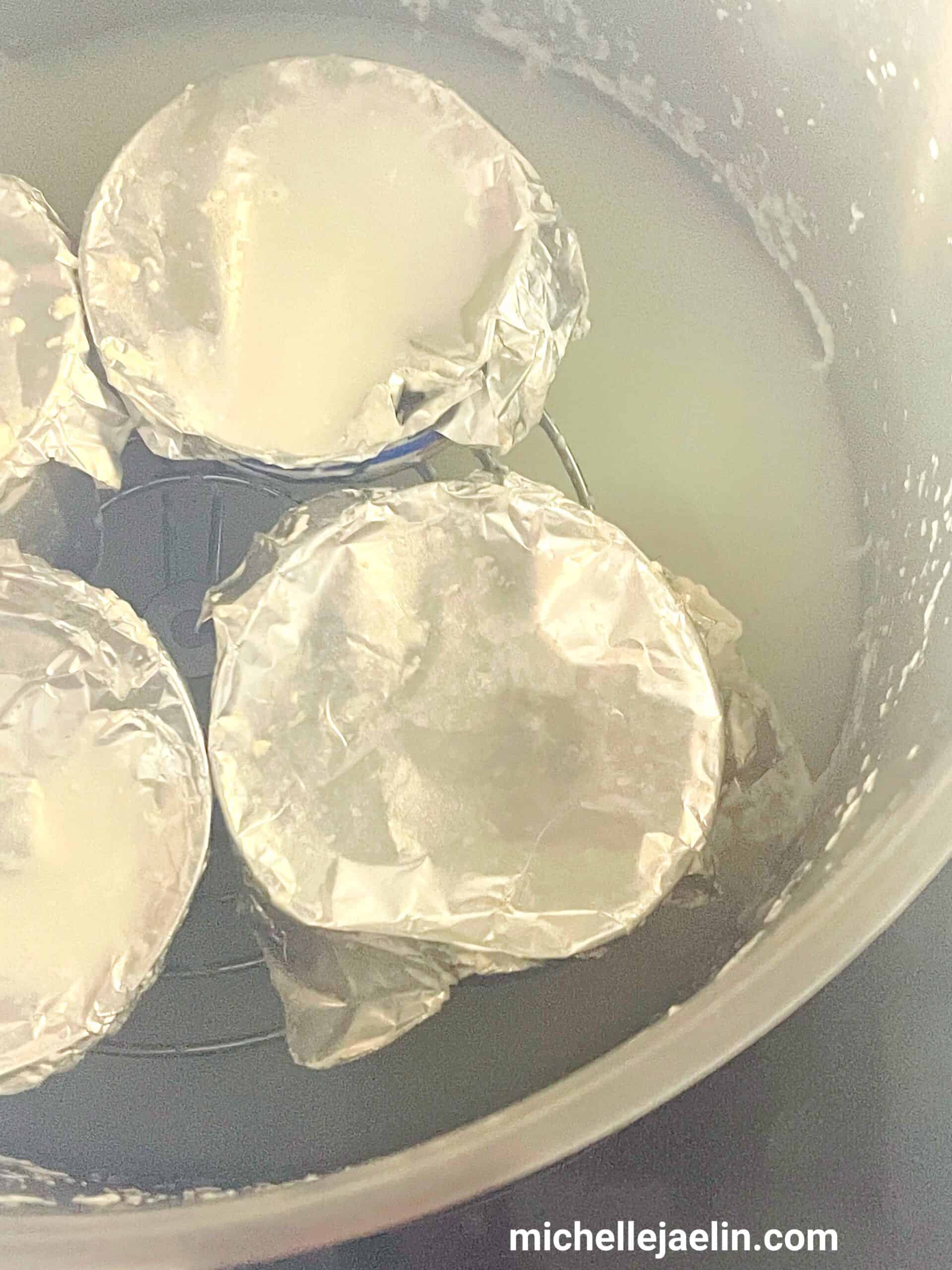 4 bowls/ramekins being steamed in a pot of boiling water.