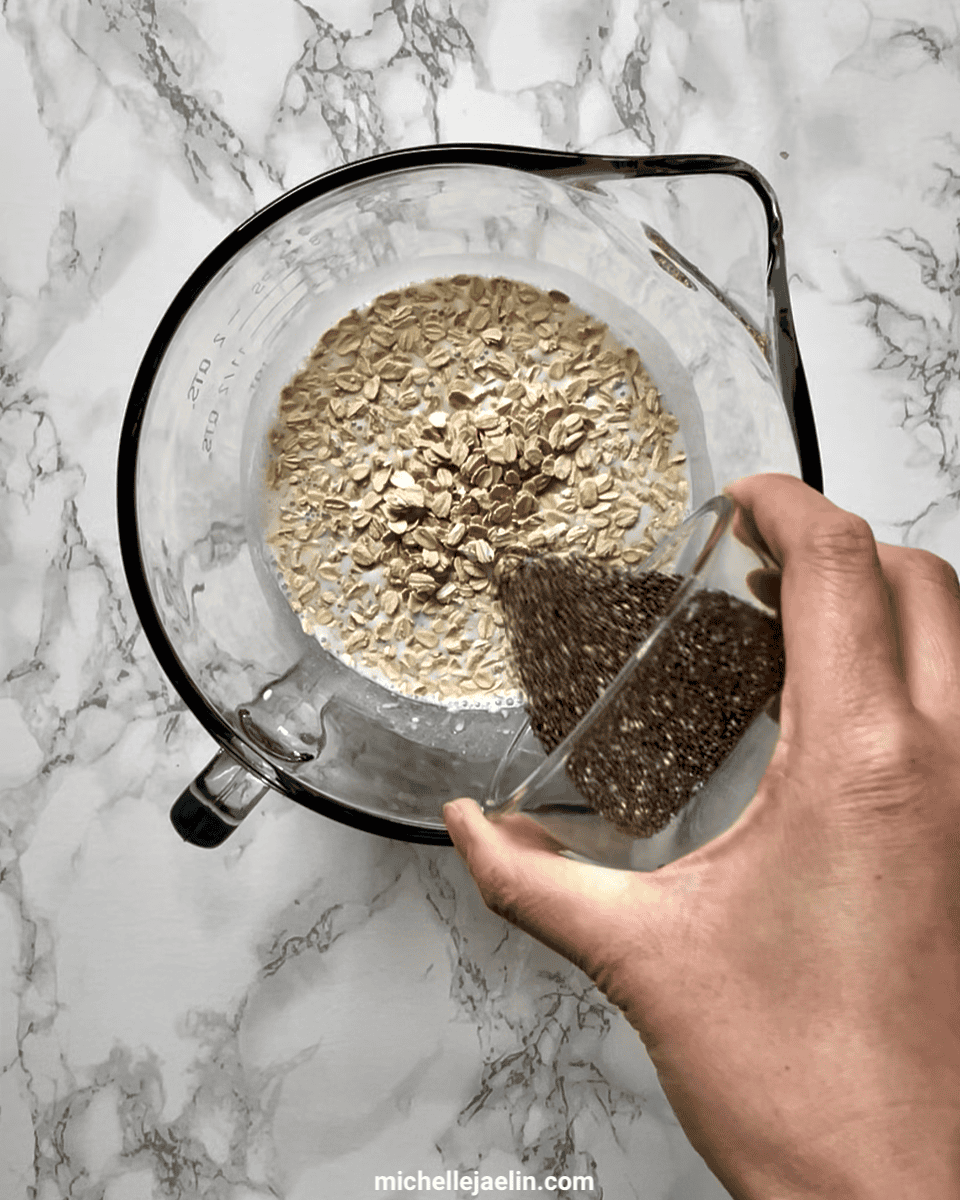 Chia seed being poured into a large bowl with rolled oats, yogurt and milk
