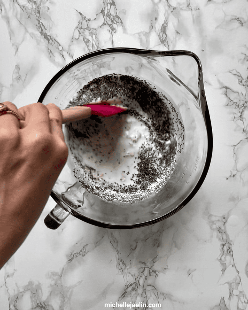 Yogurt, milk, rolled oats, chia seeds, and honey or maple syrup being mixed together in a large bowl