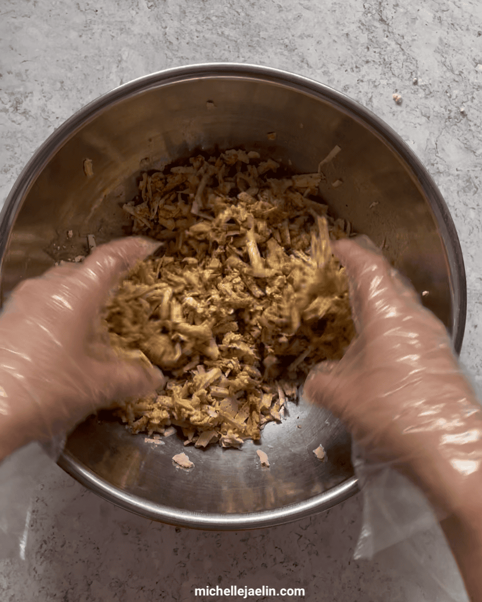 shredded tofu being mixed together by hand