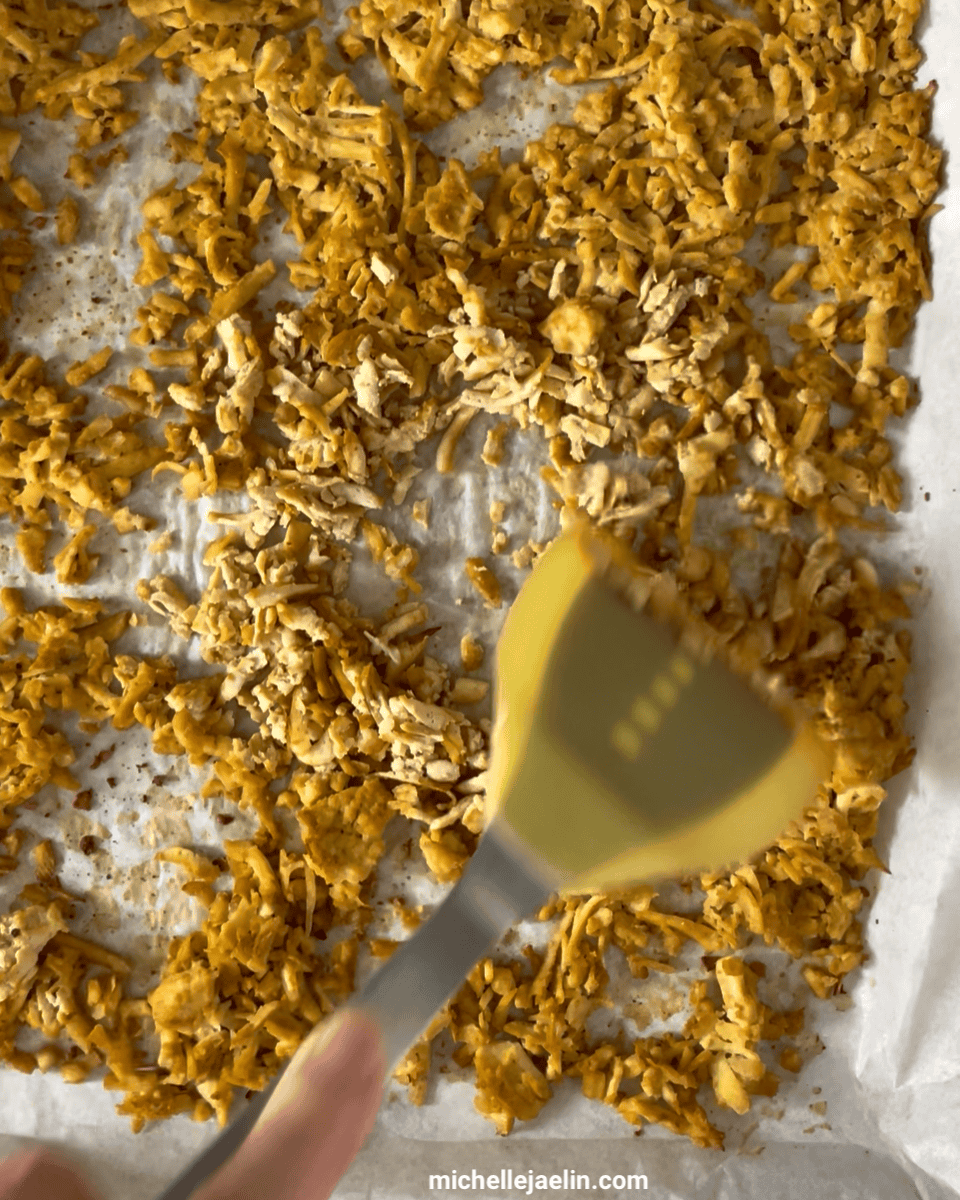 shredded tofu being flipped on the baking sheet