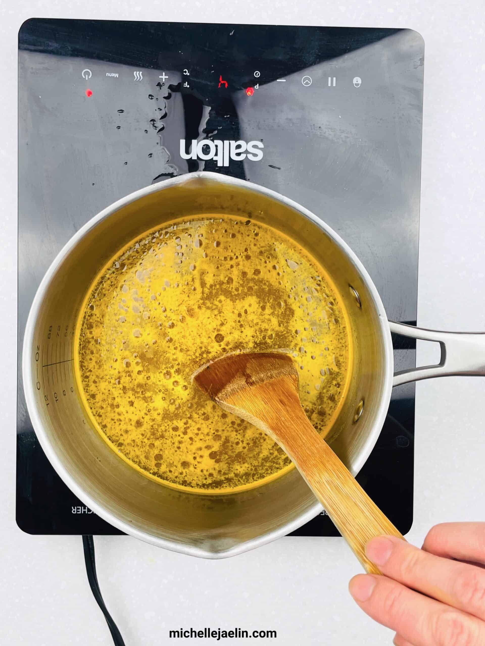 Pot with vegetable stock and ingredients with wooden spoon mixing it together