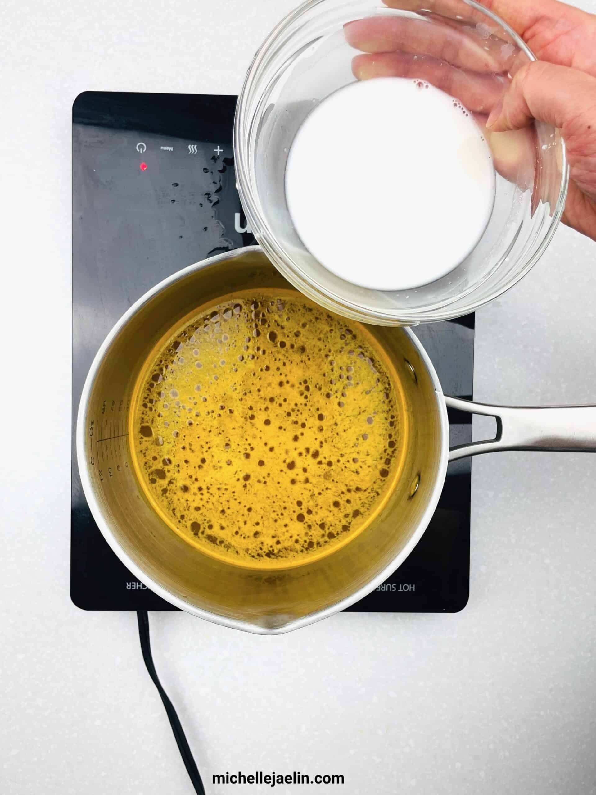 Pot with soup with small bowl of cornstarch water mixture being added to pot