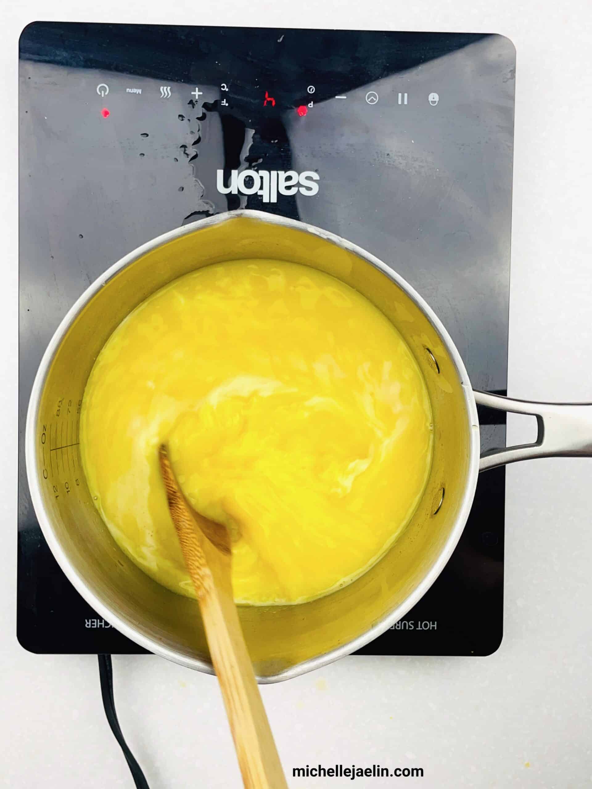 Visible egg white and yolk being swirled in pot