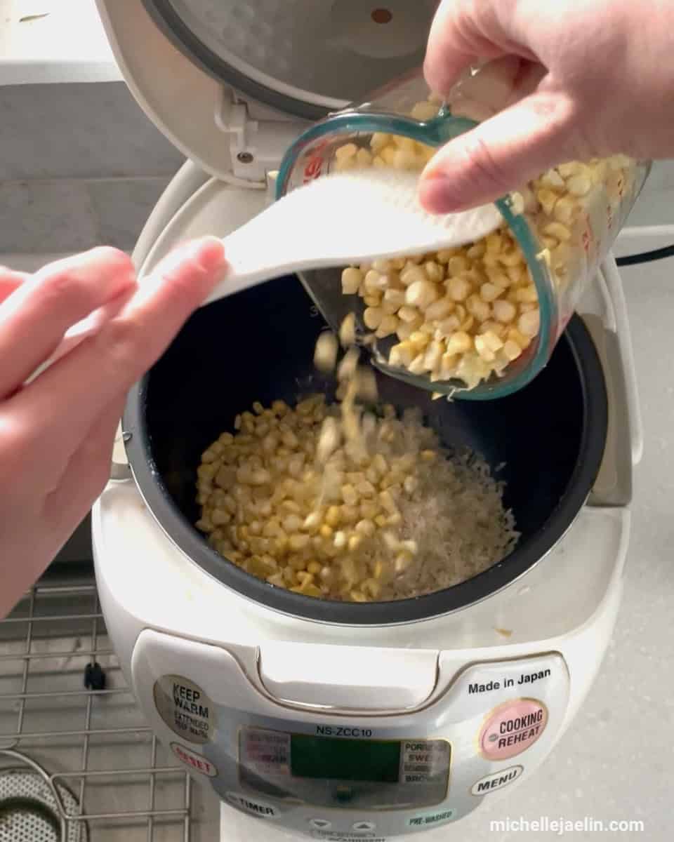 corn kernels being added to rice cooker with rice paddle