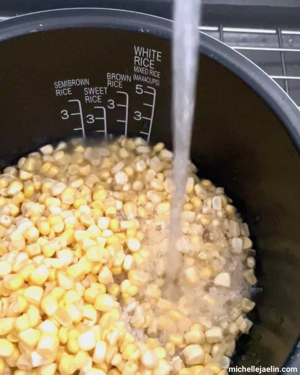 water being added to rice cooker inner pot with rice and corn kernels
