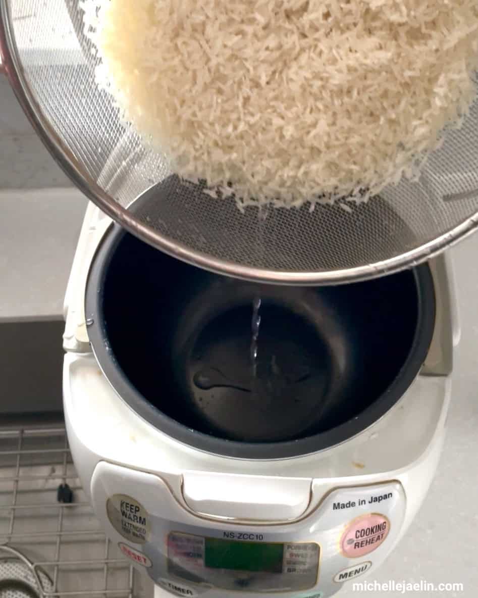 washed rice in colander being poured into rice cooker