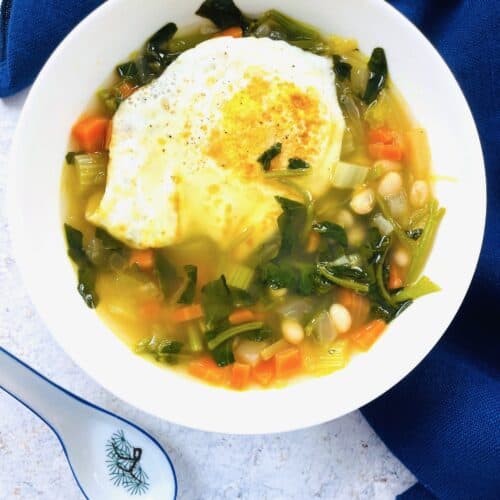 Beans and Watercress Greens Soup in a bowl with a spoon in bottom left hand corner