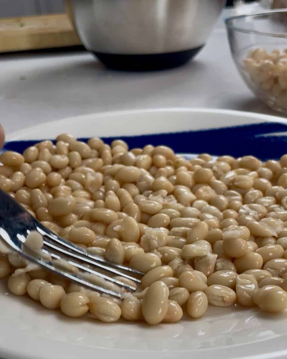 Beans on plate being mashed with a fork