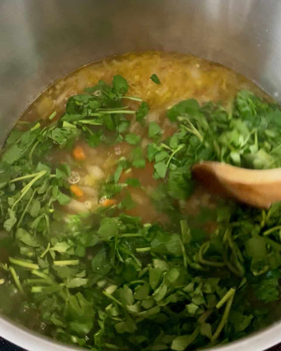 Watercress added to the pot being stirred