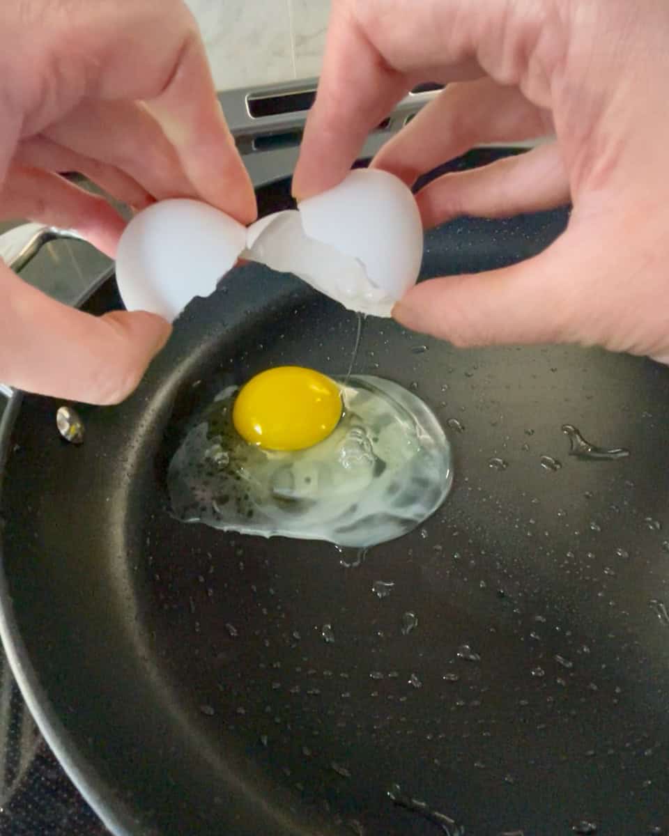Egg being cracked on a heated pan