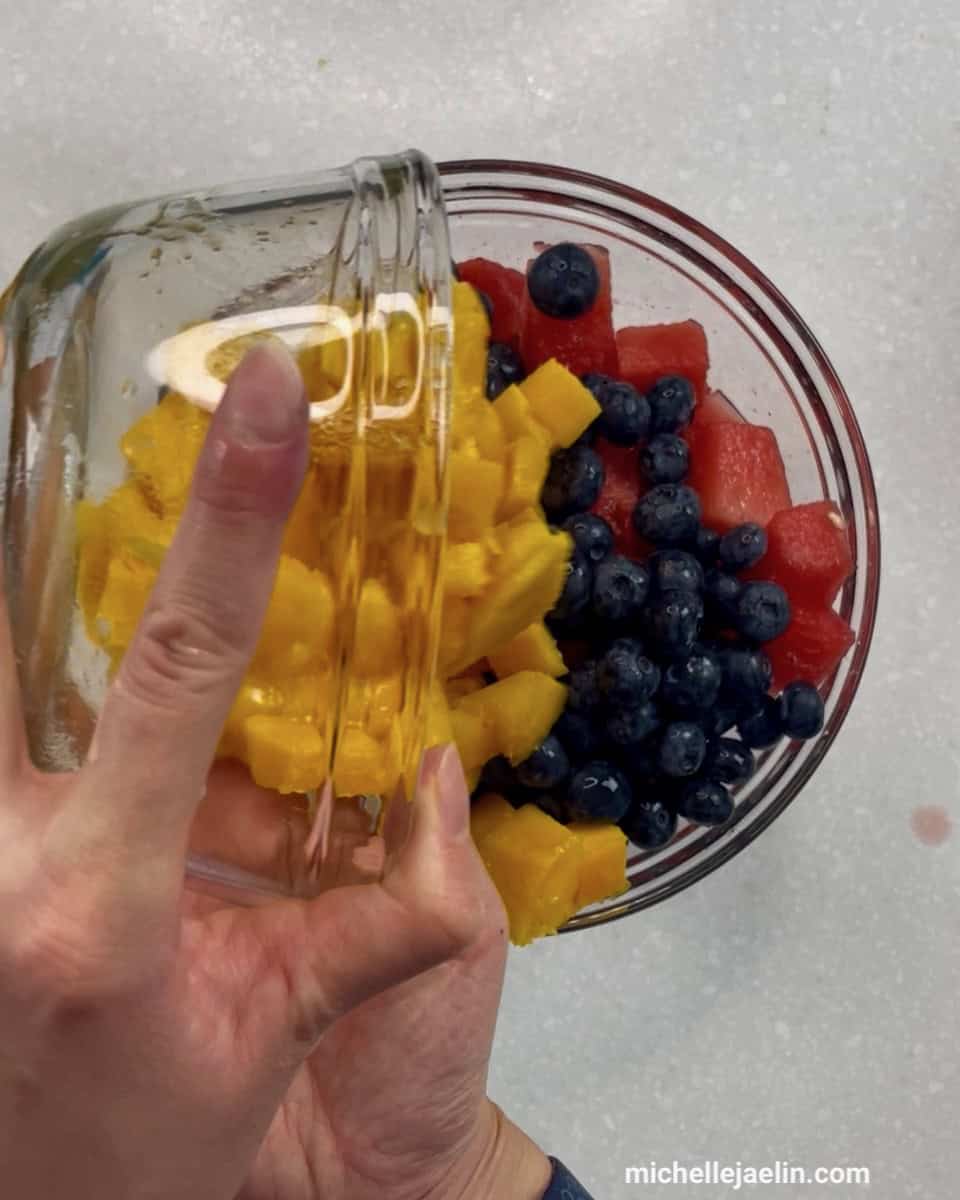 watermelon, mango and blueberries being added to a bowl