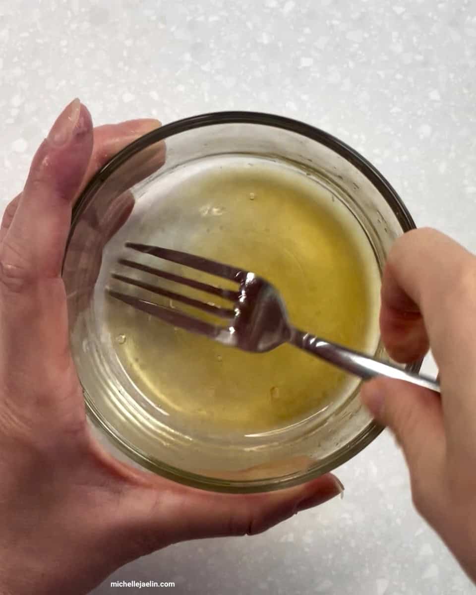 lime juice, maple syrup or honey and sea salt being whisked together with a fork in small bowl